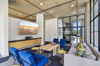 A modern living room with blue chairs and a wooden coffee table.